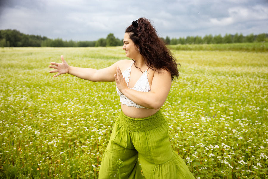 Femme pratiquant le Qi Gong dans un champ fleuri.