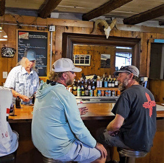 Travelers sitting at the bar counter chatting with staff inside the unpretentious VC Tavern.