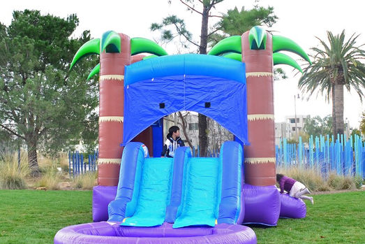 Kids playing in Caribbean inflatable bounce house with dual slides