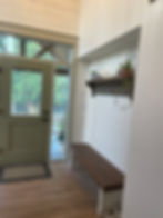 Entryway with light green door, wooden bench, and decorative shelf