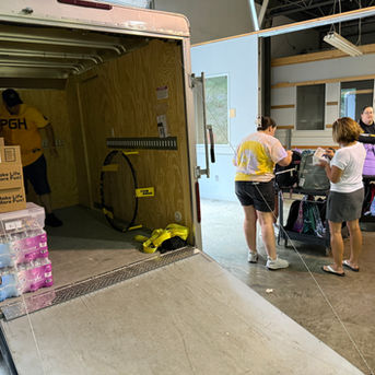 People loading boxes and supplies into a trailer for an event or donation.