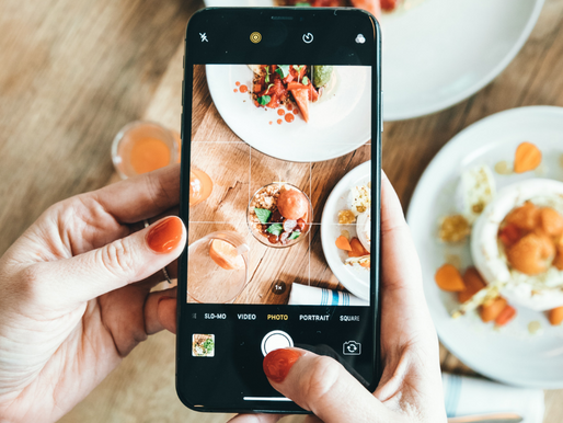 Woman holding a phone while taking a picture of her food