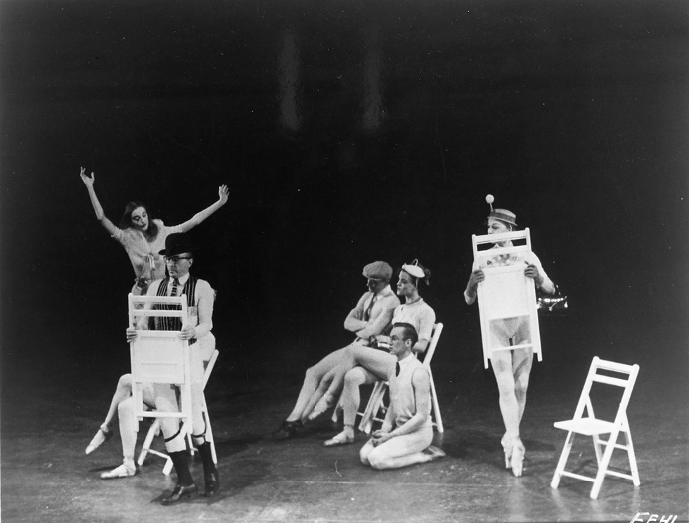 Balanchine (standing front, holding chair) and Tanaquil LeClercq (behind with arms lifted). Photo by Martha Swope, 1956.