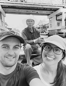 Coppia sorridente fa un selfie, uomo anziano dietro. Un viaggio in barca.