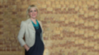 Kirsten Goodwin (Career Coach, Executive Coach, expert in Career Coaching) standing in front of a brick wall, smiling)