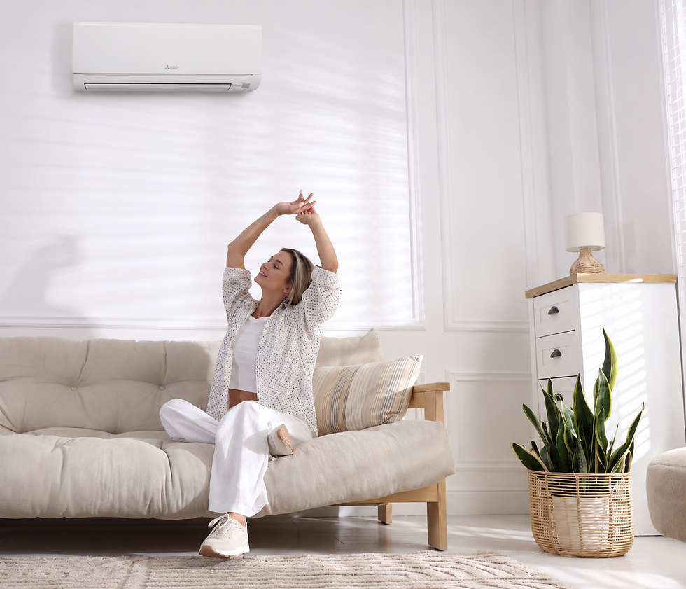 A young woman sits on a beige couch, enjoying the cooling comfort of her Mitsubishi Mini-split AC system.