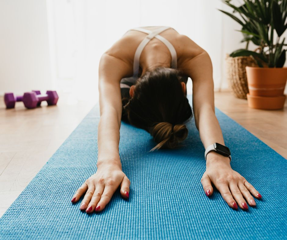 a woman stretches on a yoga mat