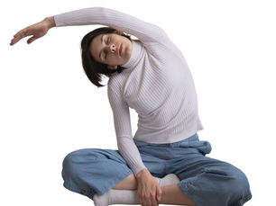 woman stretches to her side while sitting cross legged on the floor