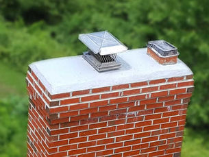 a red brick chimney with a stainless steel chimney cap