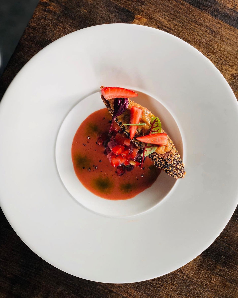 Tuna duo with toast and strawberry gazpacho on a white bowl. A seasonal offering at iconiq pulling on French cooking tradition.