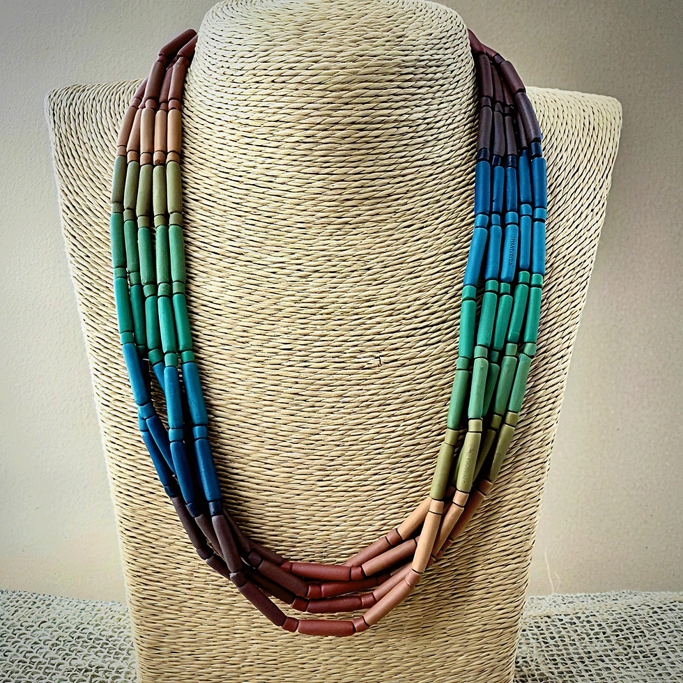 Colar curto em cerâmica fosca 5 voltas canutilhos sobre um manequim feito de fibras natuarais amareladas, que por sua vez, está sobre um fundo branco.