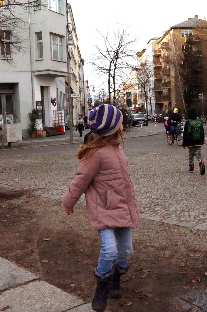 A kid playing in the playground in a wintery Berlin. 