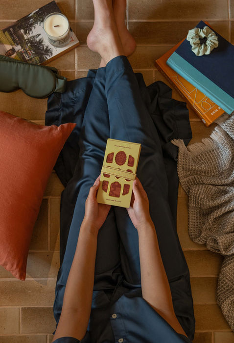 A lady in a cosy lounge wear holding a Lunar New Year red packet.