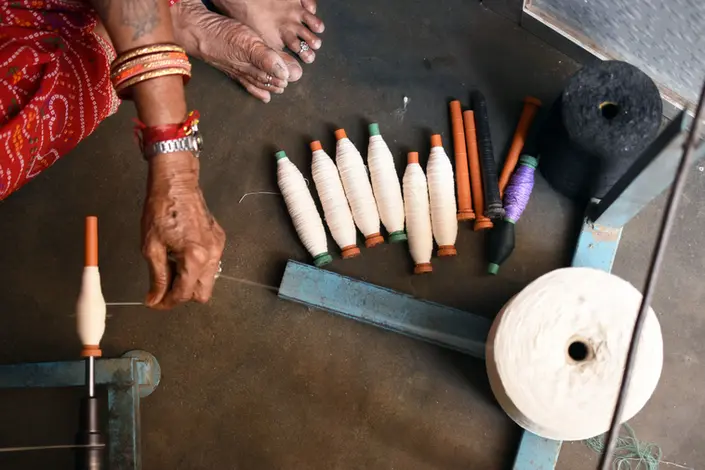 An Indian woman is spooling the recycled yarn.