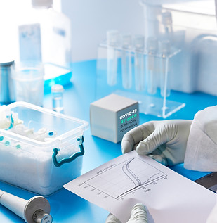 researcher wearing gloves looking at a report at lab desk with labe vials