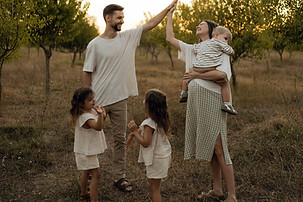 Family high-fiving in an orchard with three children