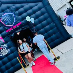 Guests gathered at a red-carpet inflatable nightclub entrance with balloons