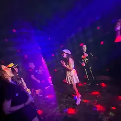 Guests dancing in costume under purple and red nightclub lighting