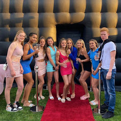 Group of friends posing on a red carpet outside an inflatable nightclub