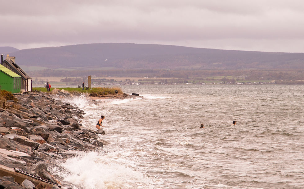 Women about to dive in to the stormy seas in Scotland to go wild swimming