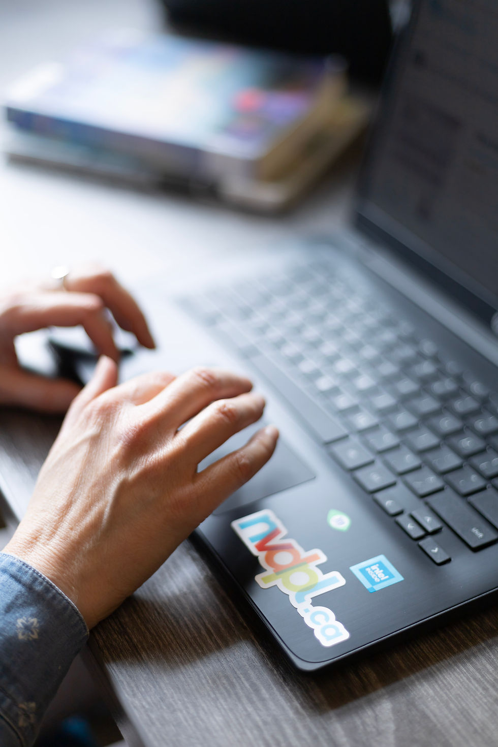 A hand is hovering on a close up of a laptop. The laptop has a sticker with "nvdpl.ca"
