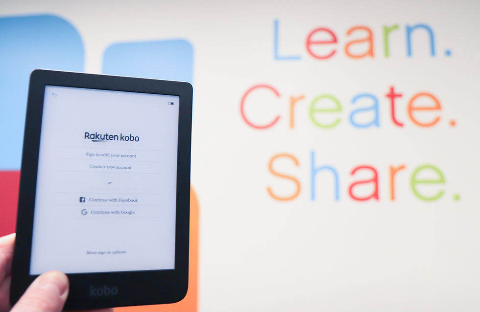 An ereader is held up against a wall with the words "Learn. Create. Share." in different colors.