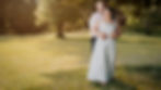 A couple shares a warm embrace in a sunlit meadow at golden hour.