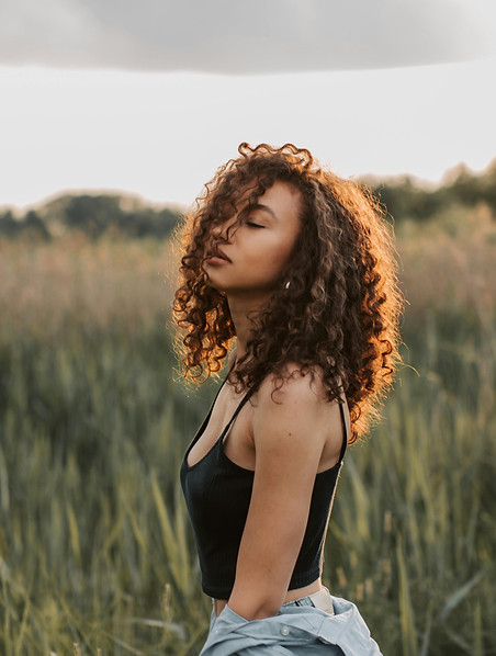 Woman of color eyes closed taking a deep breath in a field