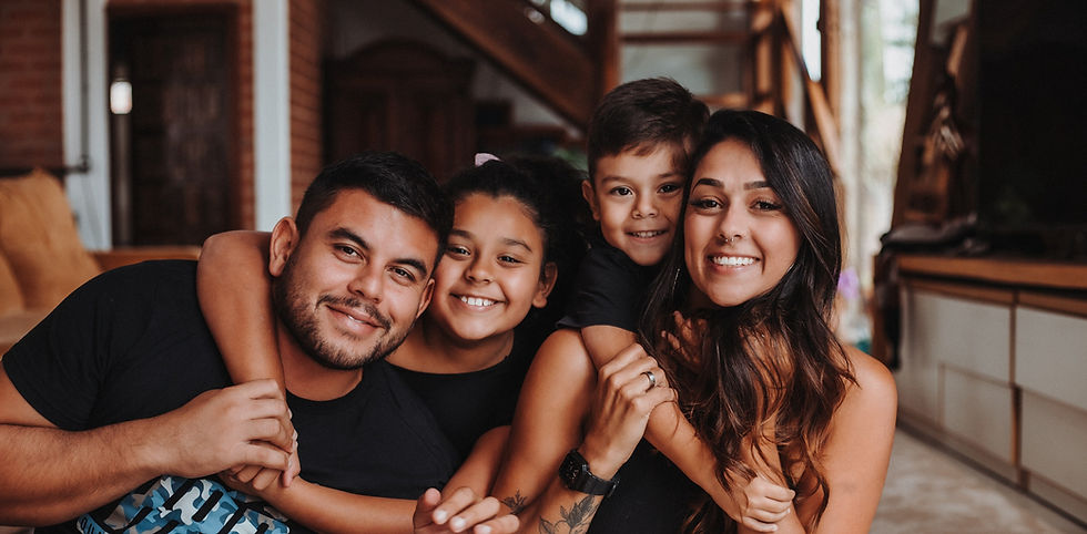 A family of four smiling and holding each other.