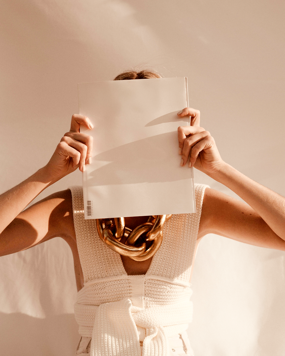 A woman holding a blank magazine which covers her face.