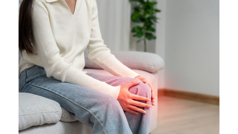 Frau, die auf dem Sofa sitzt und sich schmerzhaft das Knie hält.