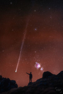Comet and Orion Nebula in the sky behind young boy standing on rock