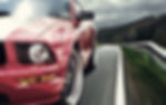Red Mustang driving on road
