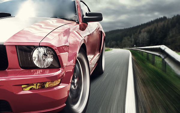 Red Mustang driving on road