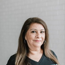 Female preschool teacher poses in white brick hallway at early learning center in Houston, TX.