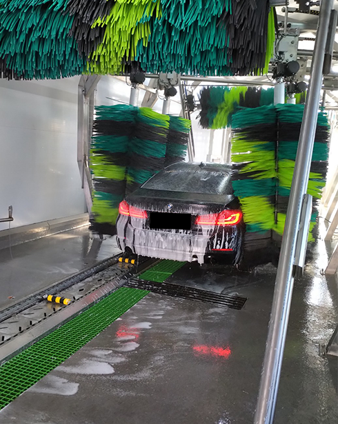 Car inside automated car wash with foam and brushes at Massen Shopping Center
