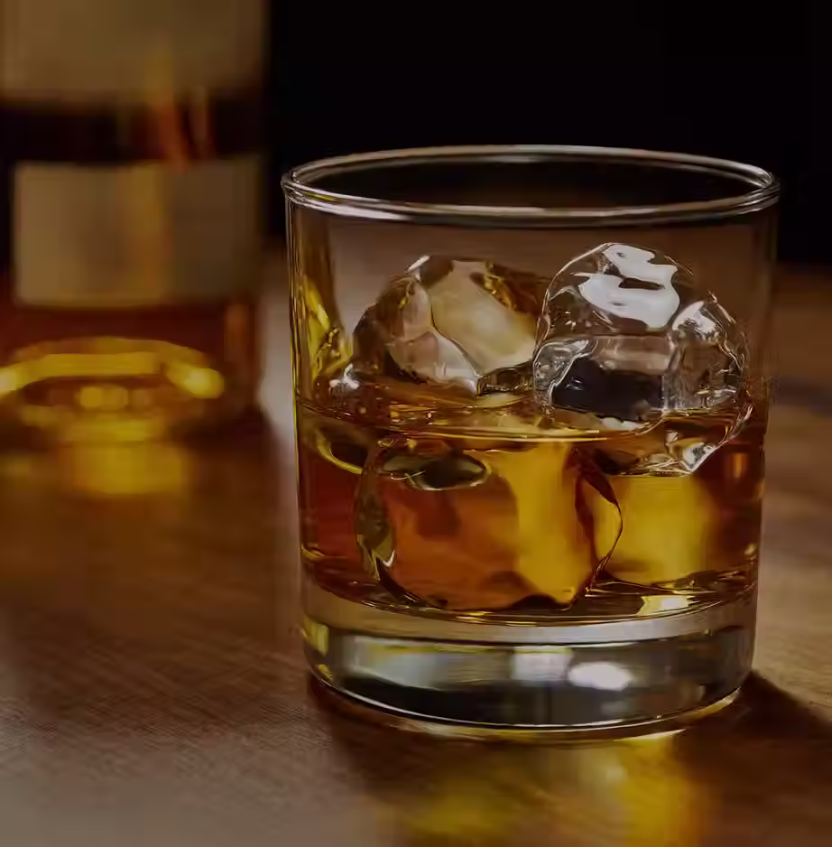 Gefülltes Whiskyglas mit Eiswürfel auf Holztisch.