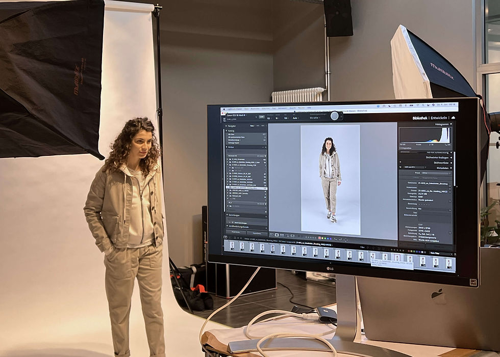 Model vor einem weißen Hintergrund, ein Monitor zeigt das Foto mit Spezifikationen.