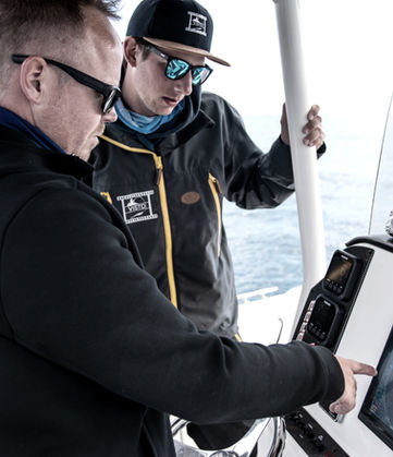 Captain using electronics and fishfinder at the helm of a Chasing Blue boat