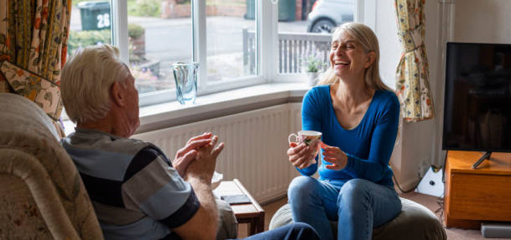 Woman holding a tea cup talking to a man sitting in a recliner