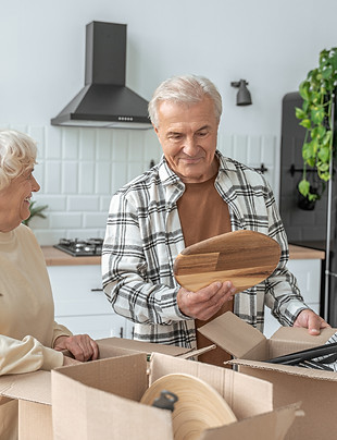 Mature couple standing at the kitchen with moving boxes at the new house.jpg