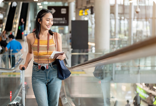 gorgeous-young-asian-female-tourist-passenger-is-airport-escalator-carrying-her-luggage.pn