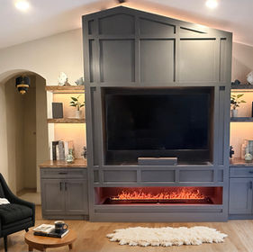 Sleek gray media wall with fireplace and shelving custom built by Spirit Building Group in Fort Myers home.