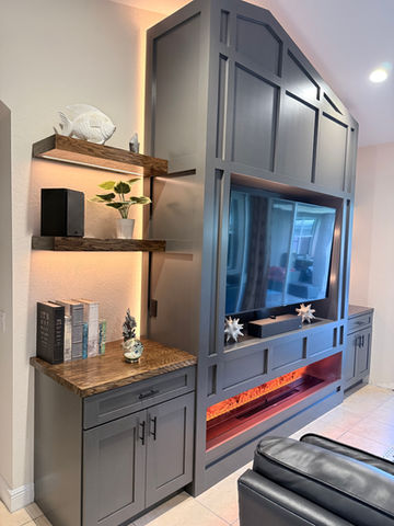 Sleek gray media wall with brown oak shelves and fireplace burning orange.
