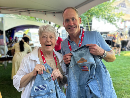 Guests at Folds of Honor event in Minnesota smiles as they personalize a denim jacket with custom embroidered and leather patches at the Hip Hues live patching activation.