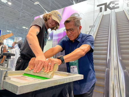 Guests screen printing custom tote bags live at a branded Hip Hues activation, smiling and laughing as they pull ink across the screen.