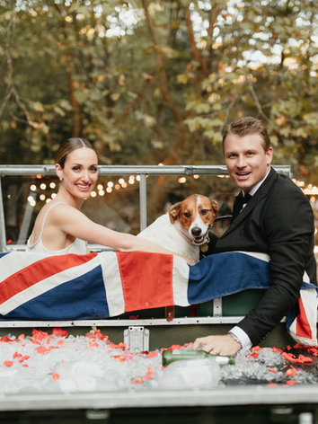 Bride and groom sharing a special moment with their dog during wedding portraits while their wedding pet attendant coordinates the session.