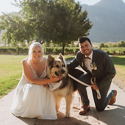Bride and groom kneeling with their dog on their wedding day