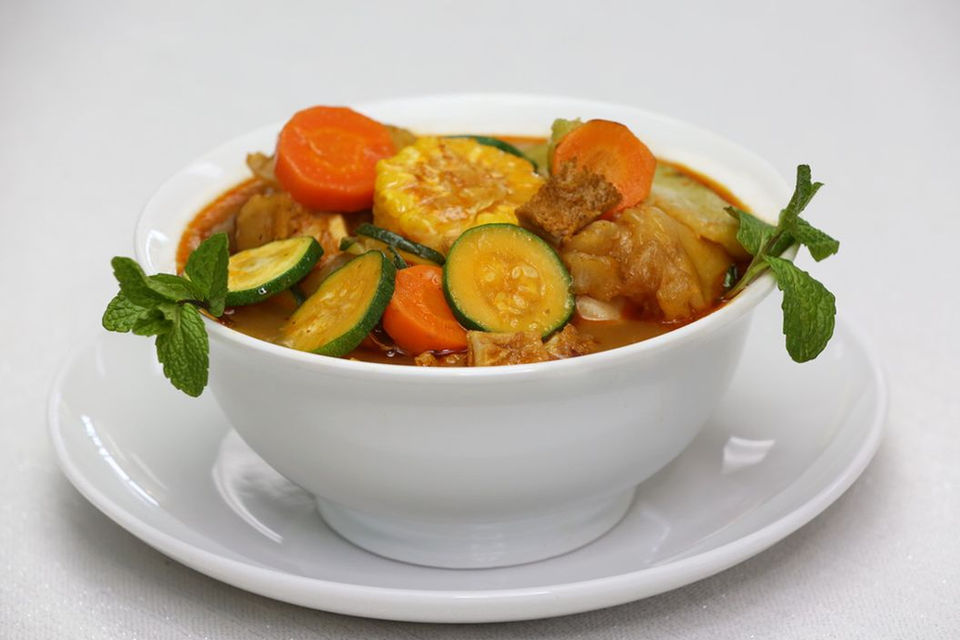 Bowl of sopa de pata with carrots, corn and other vegetables