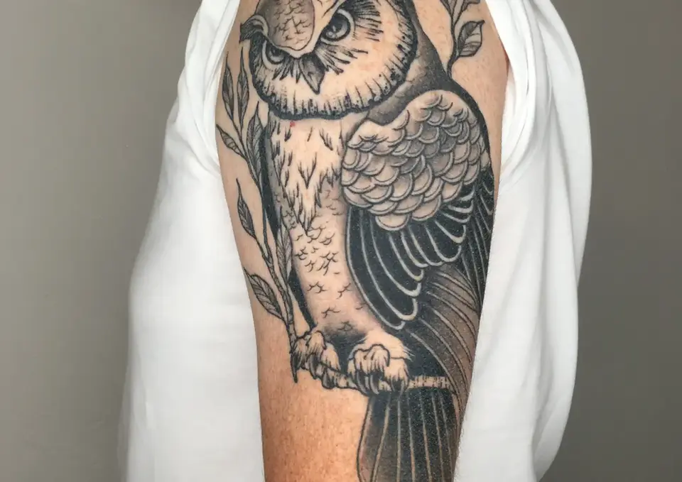 Detailliertes Eulen-Tattoo auf dem Oberarm.